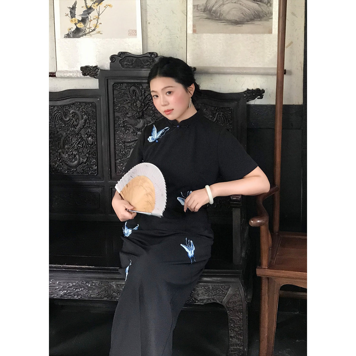 Seated view of the long black embroidered qipao dress